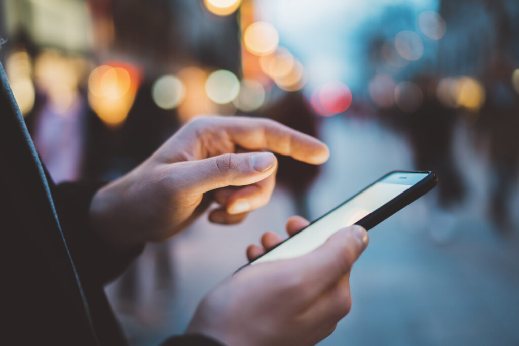Closeup of male hands typing an sms message via smartphone outsi